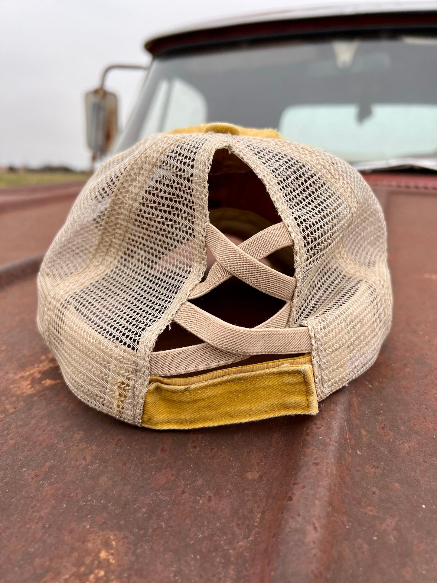 Back of mustard baseball cap with criss cross back and velcro strap
