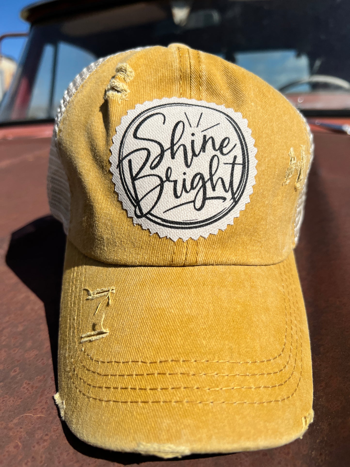 Shine Bright material patch on mustard distressed baseball cap