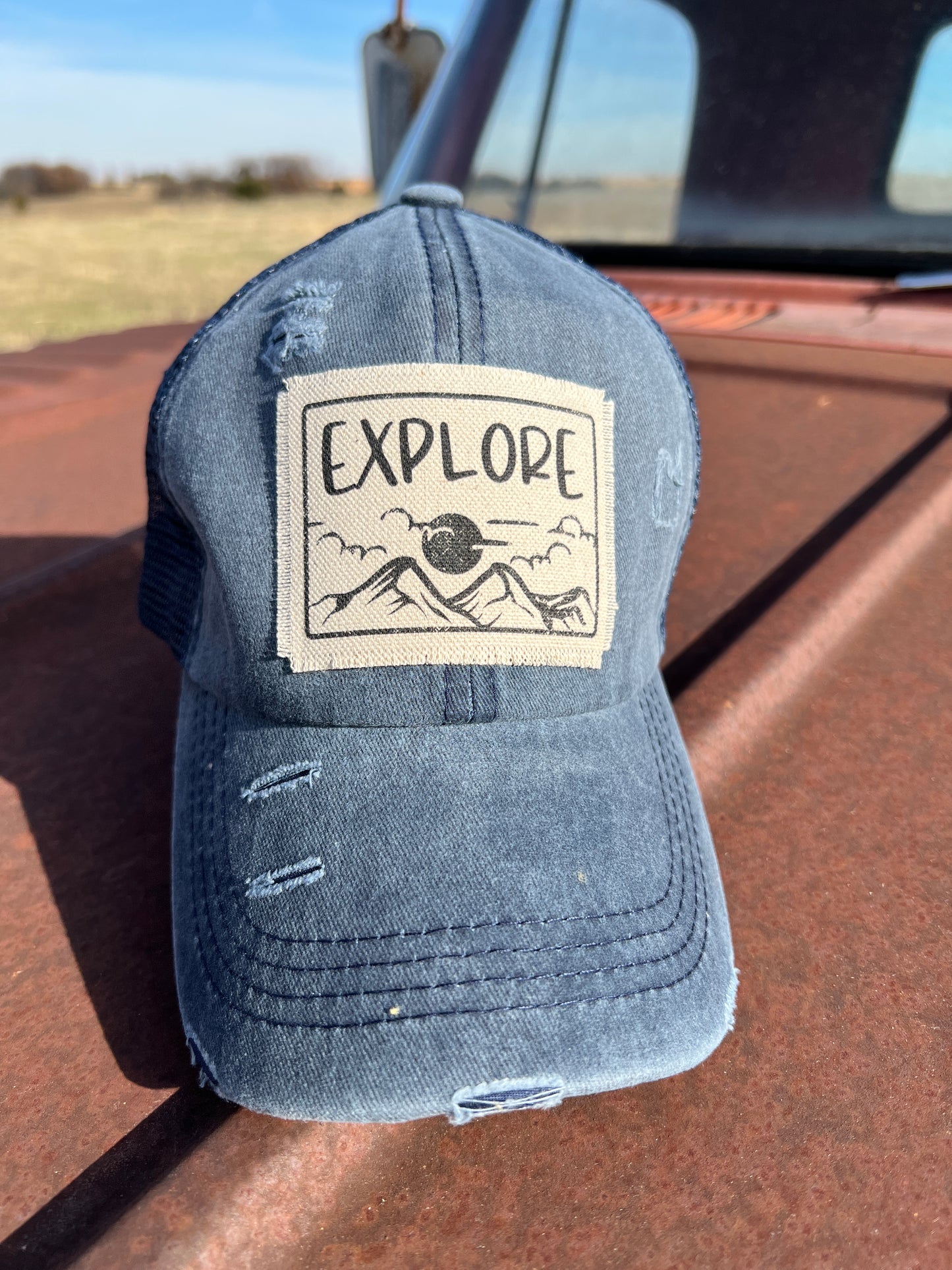 Material patch with "Explore 'graphic design on  a distressed navy baseball cap