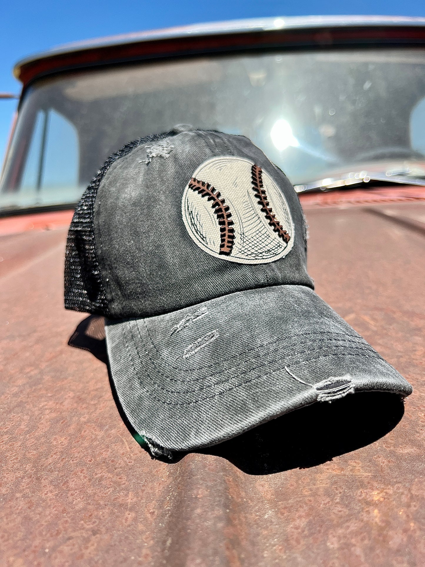 Black Distressed Trucker Cap with material baseball with leather patch. Criss-cross ponytail back