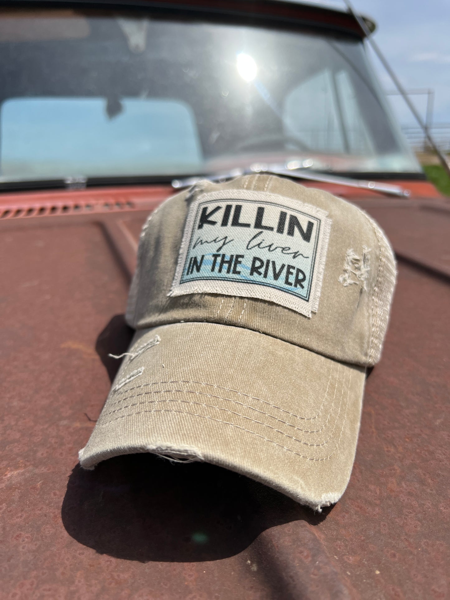 Khaki baseball cap with material patch with sayig " Killin my Liver  in the River" 
