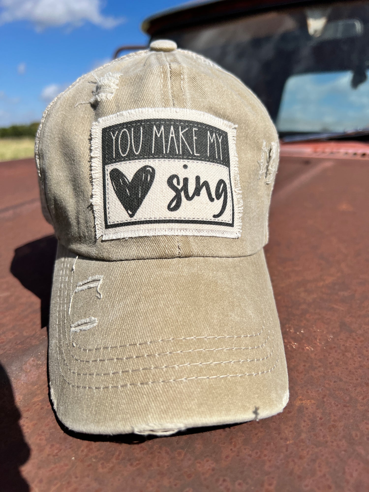 Khaki baseball cap with material patch saying You Make My Heart Sing